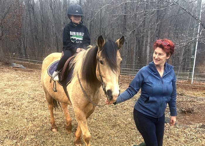 a teacher leading a student on a horse